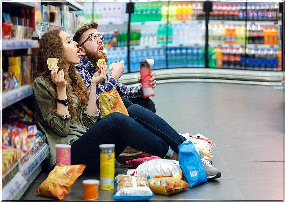 Couple eats unhealthy snacks in the supermarket