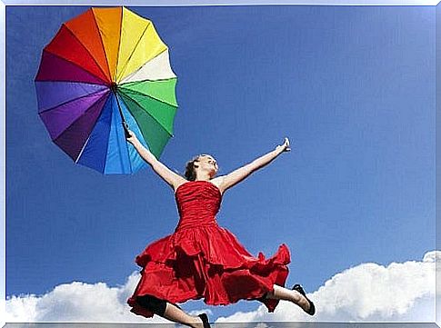 Woman jumping in the air with a rainbow umbrella